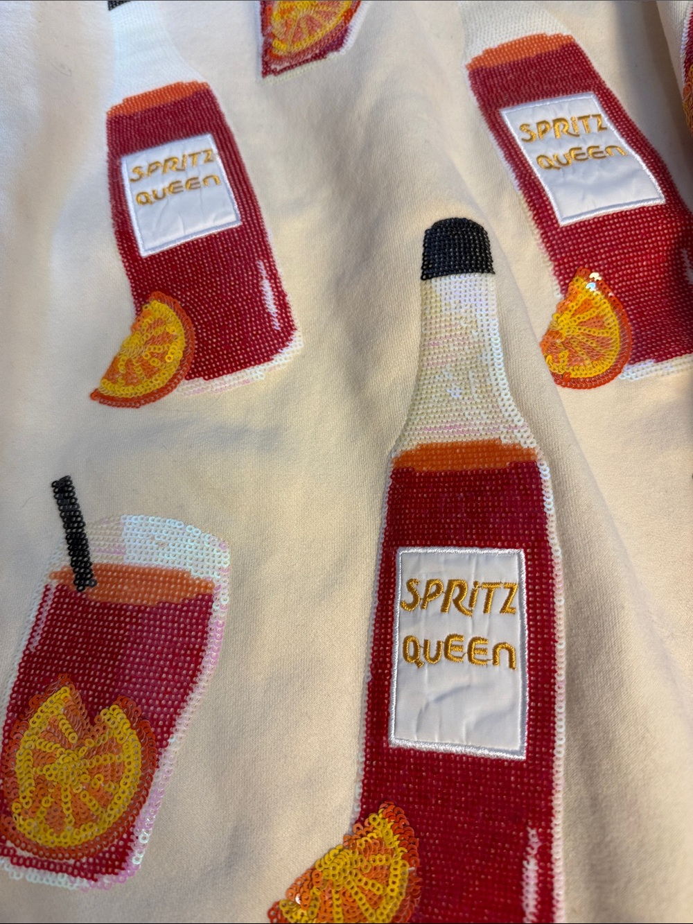 QUEEN OF SPARKLES Cream Sweater with Red & Orange Spritz Bottle Motif - Picture 2 of 4